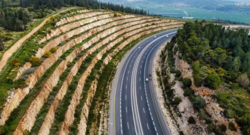Stunning aerial view of a highway winding through terraced hills and lush greenery.