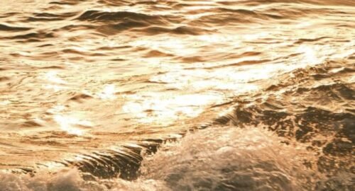 Experience the serene beauty of ocean waves illuminated by the golden hues of sunset.