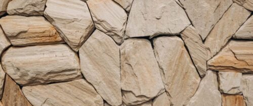 Detailed natural stone wall texture showcasing uneven rocks in beige tones.