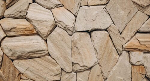 Detailed natural stone wall texture showcasing uneven rocks in beige tones.